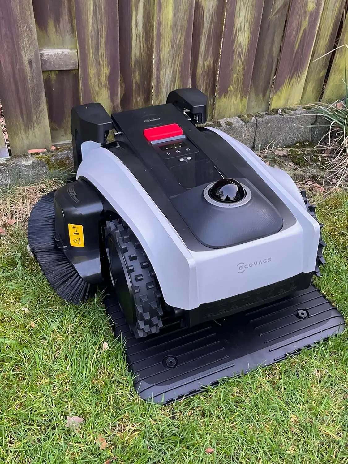 ECOVACS GOAT auf der Ladestation vor Holzzaun